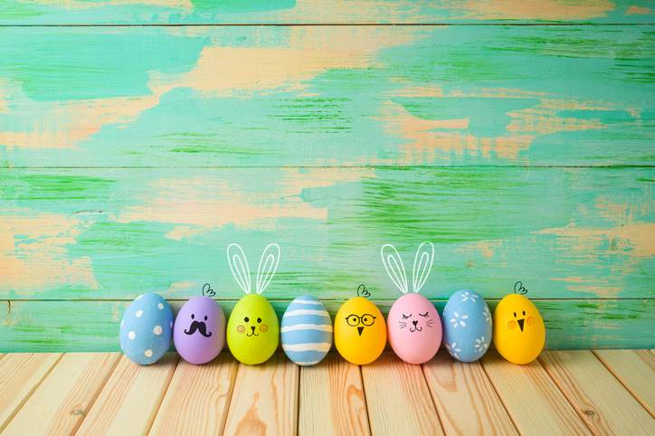 Easter eggs decorations on wooden table over colorful background Easter eggs decorations on wooden table over colorful background