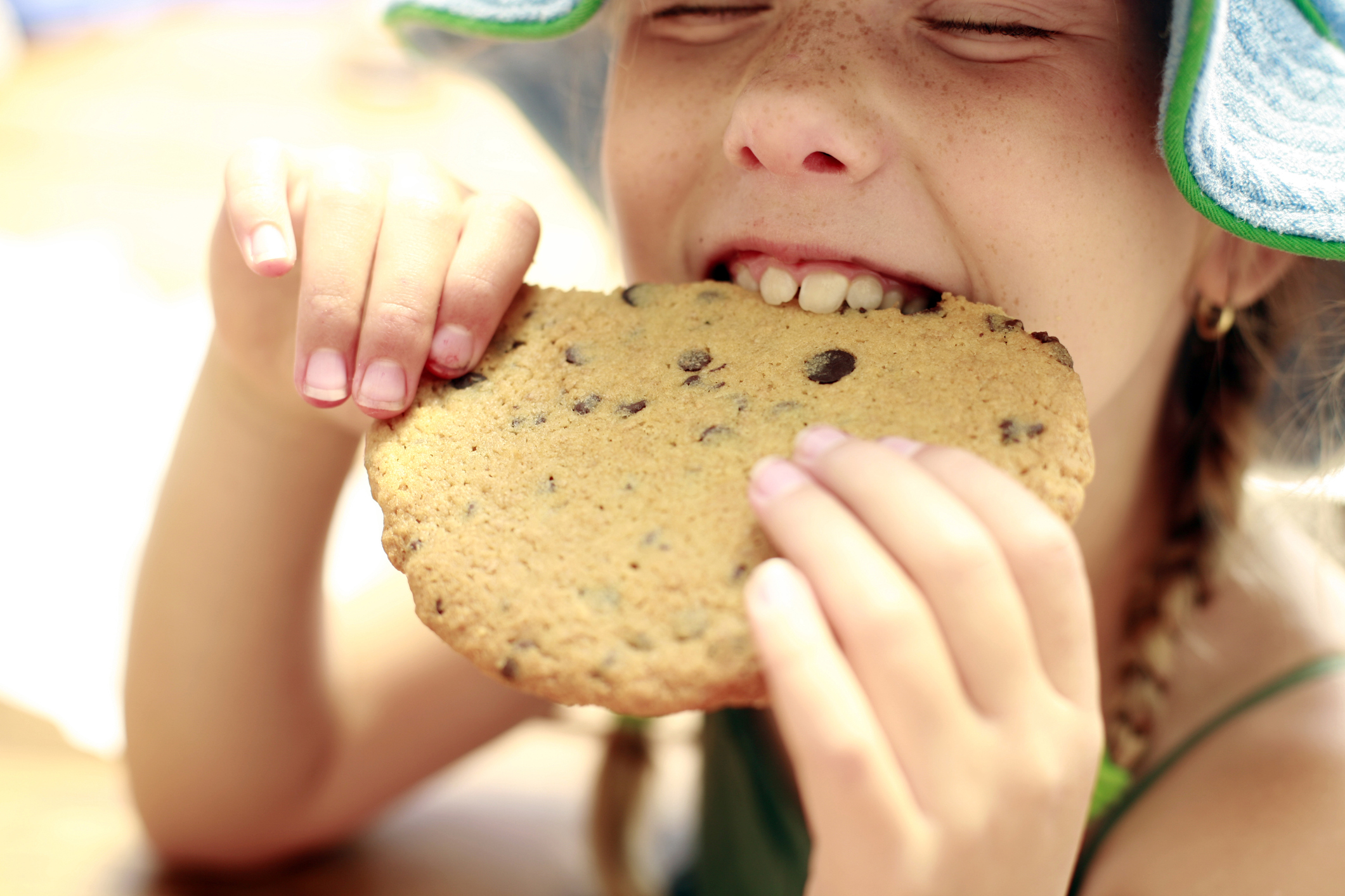 Little girl eating a big cookie.