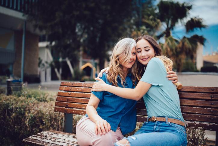 Senior mother and daughter embracing while sitting on a bench Senior mother and daughter embracing while sitting on a bench
