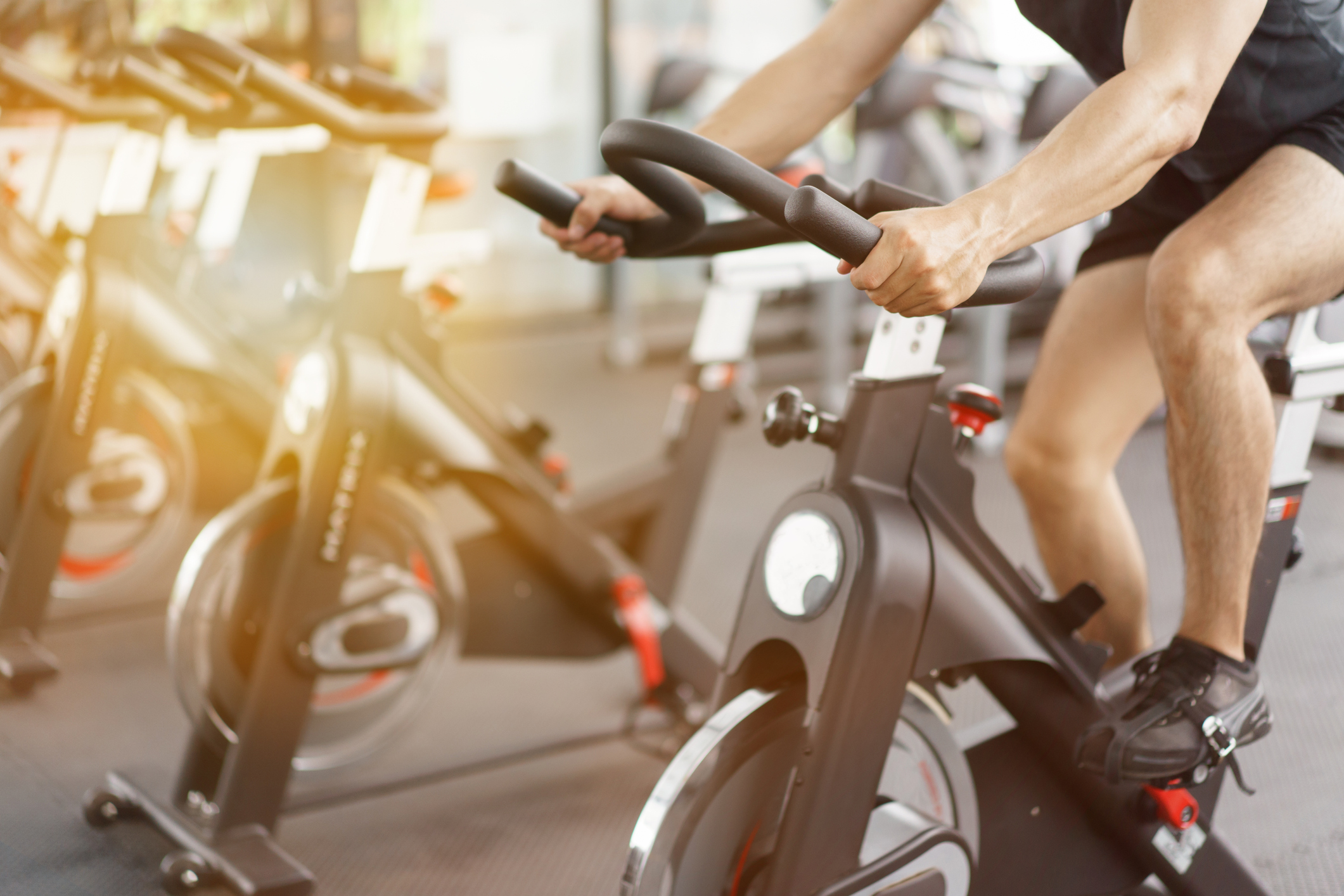 Asian man cycling on bike in fitness gym.