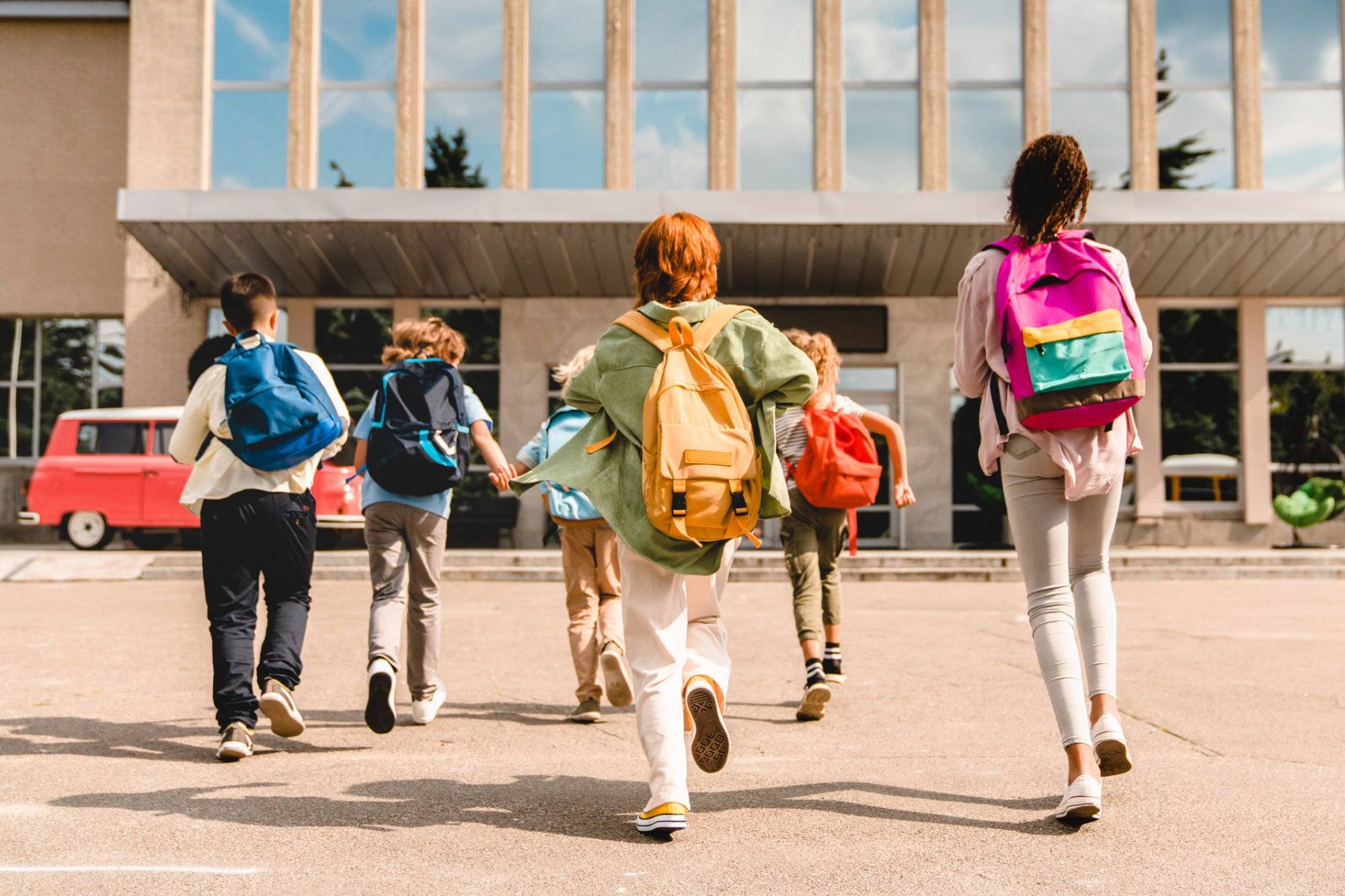 Little kids schoolchildren pupils students running hurrying to the school building for classes lessons from to the school bus. Welcome back to school. The new academic semester year start Little kids schoolchildren pupils students running hurrying to the school building for classes lessons from to the school bus. Welcome back to school. The new academic semester year start